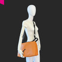 Cromia Alyson Leder-Beuteltasche in Cognac, Crossbody getragen am Modell mit verstellbarem Schultergurt
