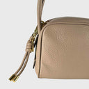 Abro Dalia Lederanhänger in Beige befestigt an Handtasche mit goldfarbener Hardware
